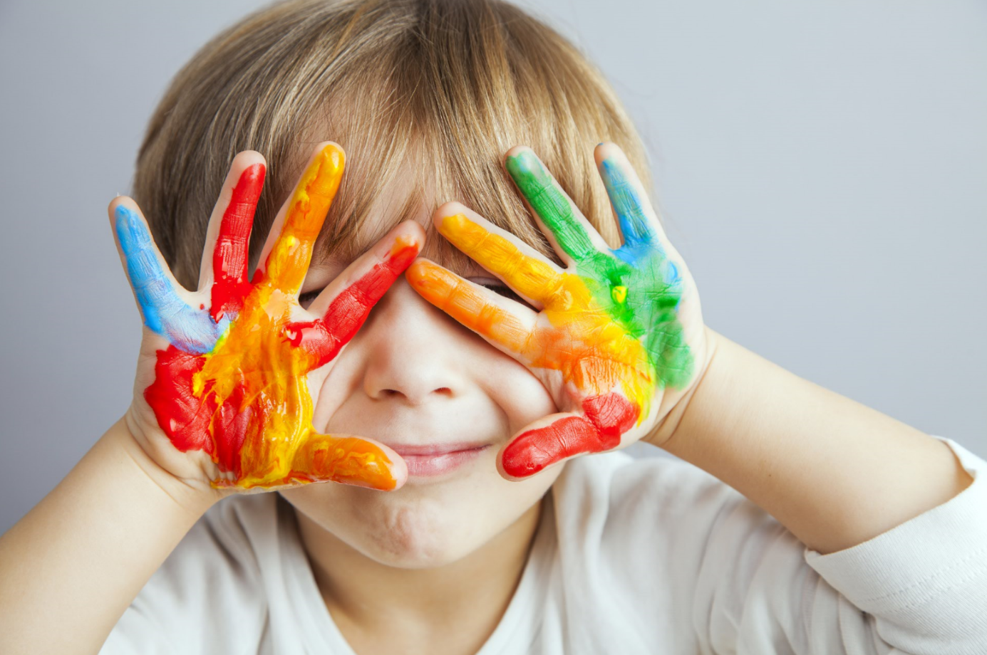 Criança brincando com tintas coloridas nas mãos